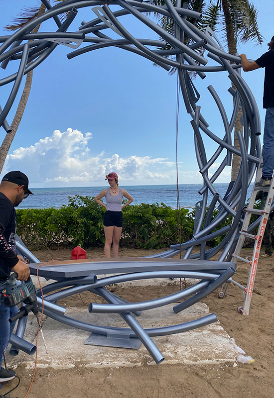 Elizabeth looks at the sculpture while the team works.