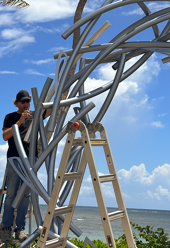 Luis Torruella at the top side of the sculpture adjusting it.