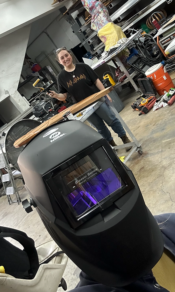 Danielle holding a paint roller while Elizabeth takes a selfie wearing a welder’s mask.