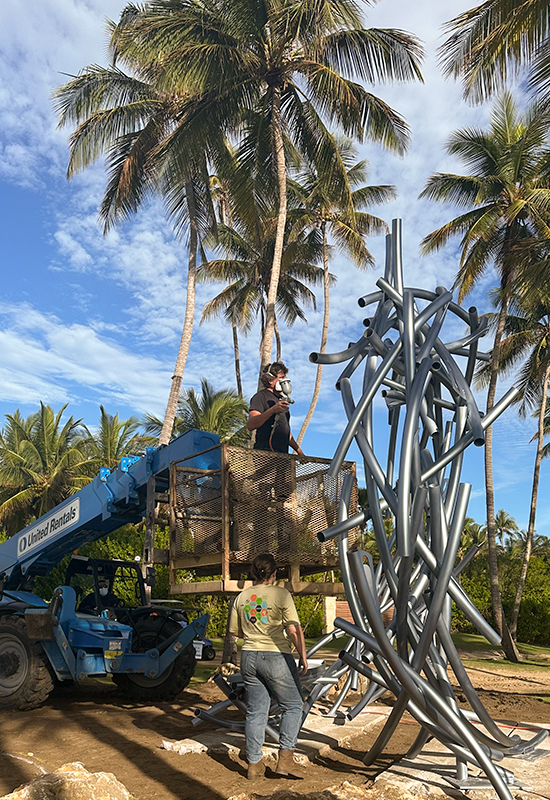 Luis Torruella inside an aerial truck platform painting the sculpture.
