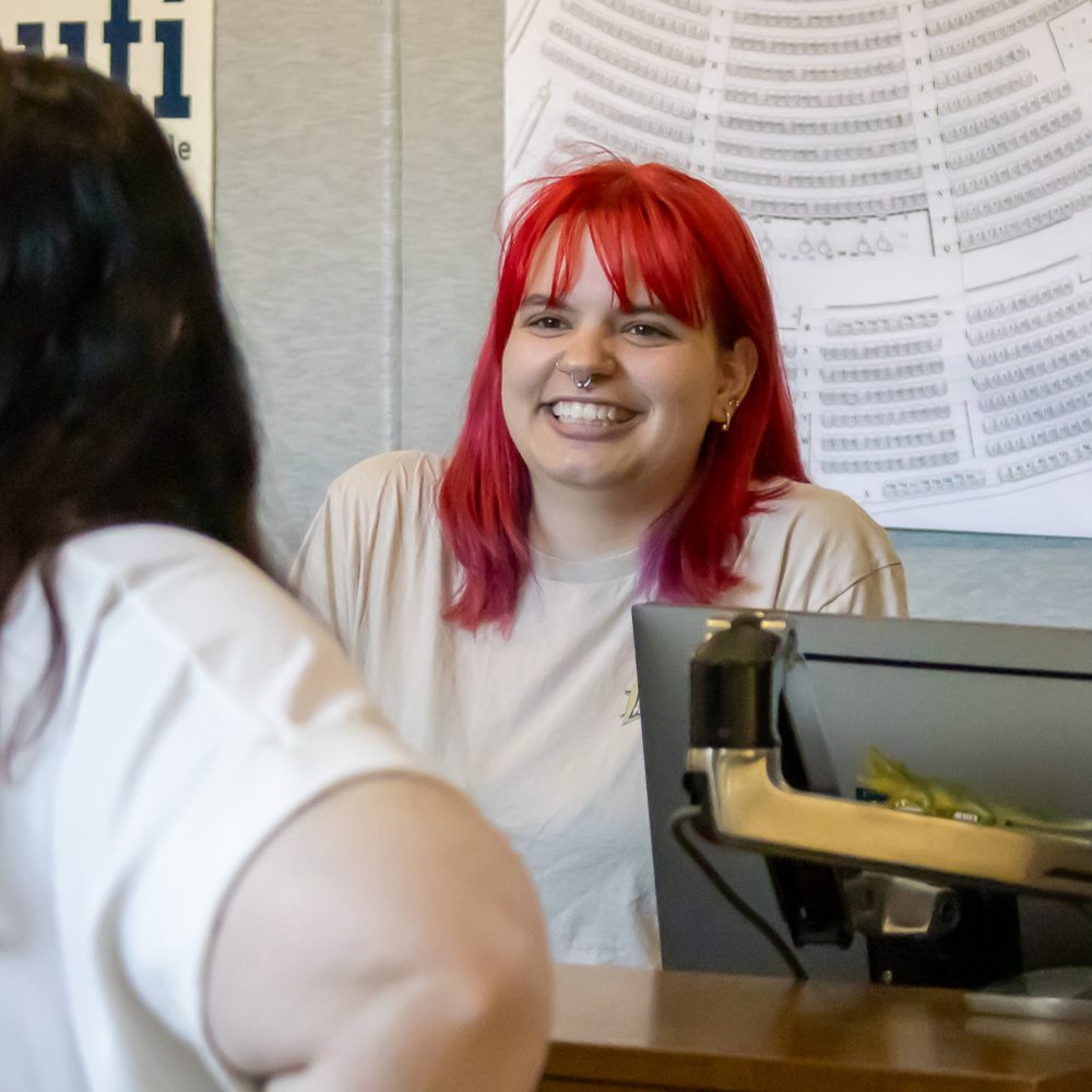 Box office student employee smiling at visitor 