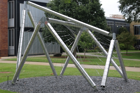 Shiny metal tubing in overlapping shapes with webs of metal stretched from pole to pole, viewed from the side