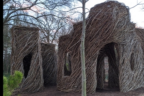 Thin saplings and branches have been woven together in the shape of cube-like buildings with arched doors and windows.