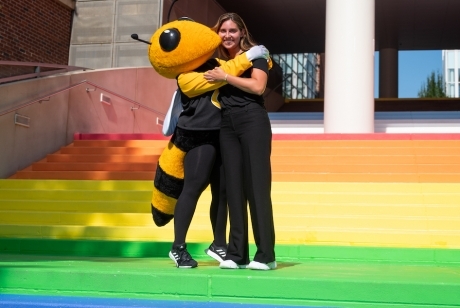 Buzz and a woman hug while standing on the Pride Stairs.