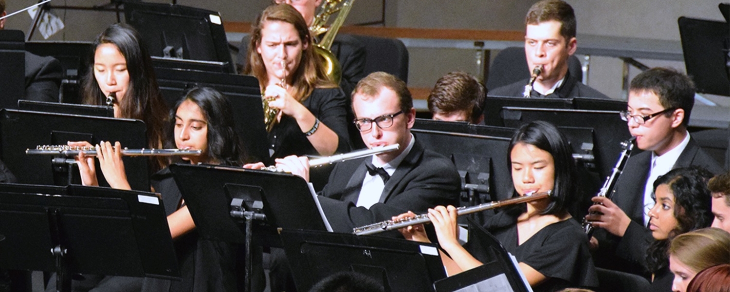 A dozen musicians in formal wear play wind instruments