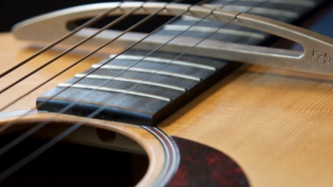 Detail of the soundhole and metal bridge with Kaki King engraved of an acoustic guitar. / Photo by Kaki King