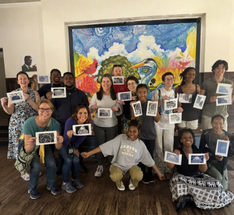 Group of people holding up art prints they made