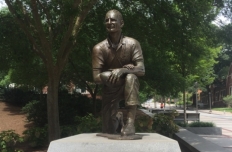 Figure of Bobby Dodd kneeling on one knee, holding a football in his left hand resting on his left knee