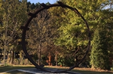 Circular band of steel, one point resting on the ground, with bars placed perpendicular to the circle almost as if it creates a ladder