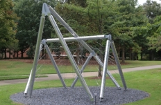 Shiny metal tubing in overlapping shapes with webs of metal stretched from pole to pole