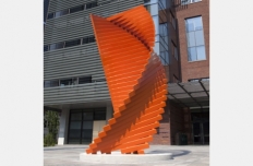 bright orange steel tubing stacked in a twisted tower