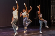 four dancers in pale blue pants and white t shirts and gloves