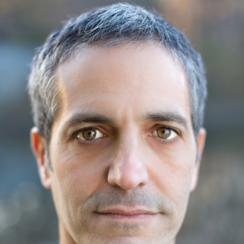 A man with close cropped grey hair stares directly at the camera.
